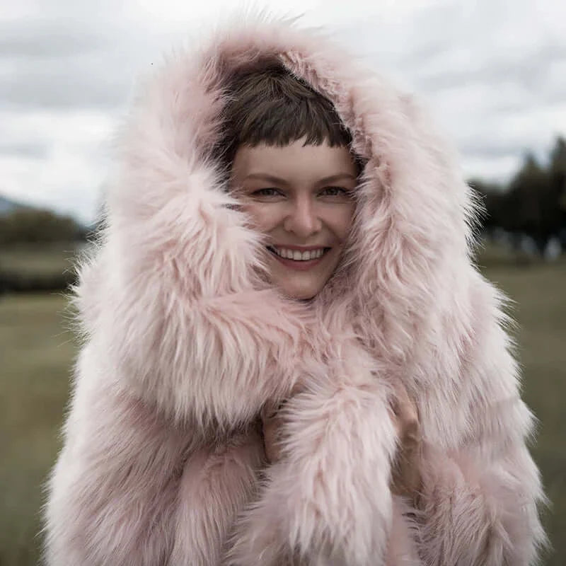 The model wearing a plush and warm pink faux fur blanket which is multi-functional and easy to wash.