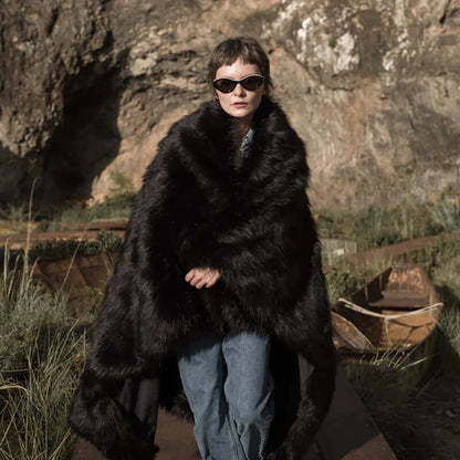 The model wearing a fluffy and warm black faux fur blanket. The blanket is multi-functional and easy to wash.
